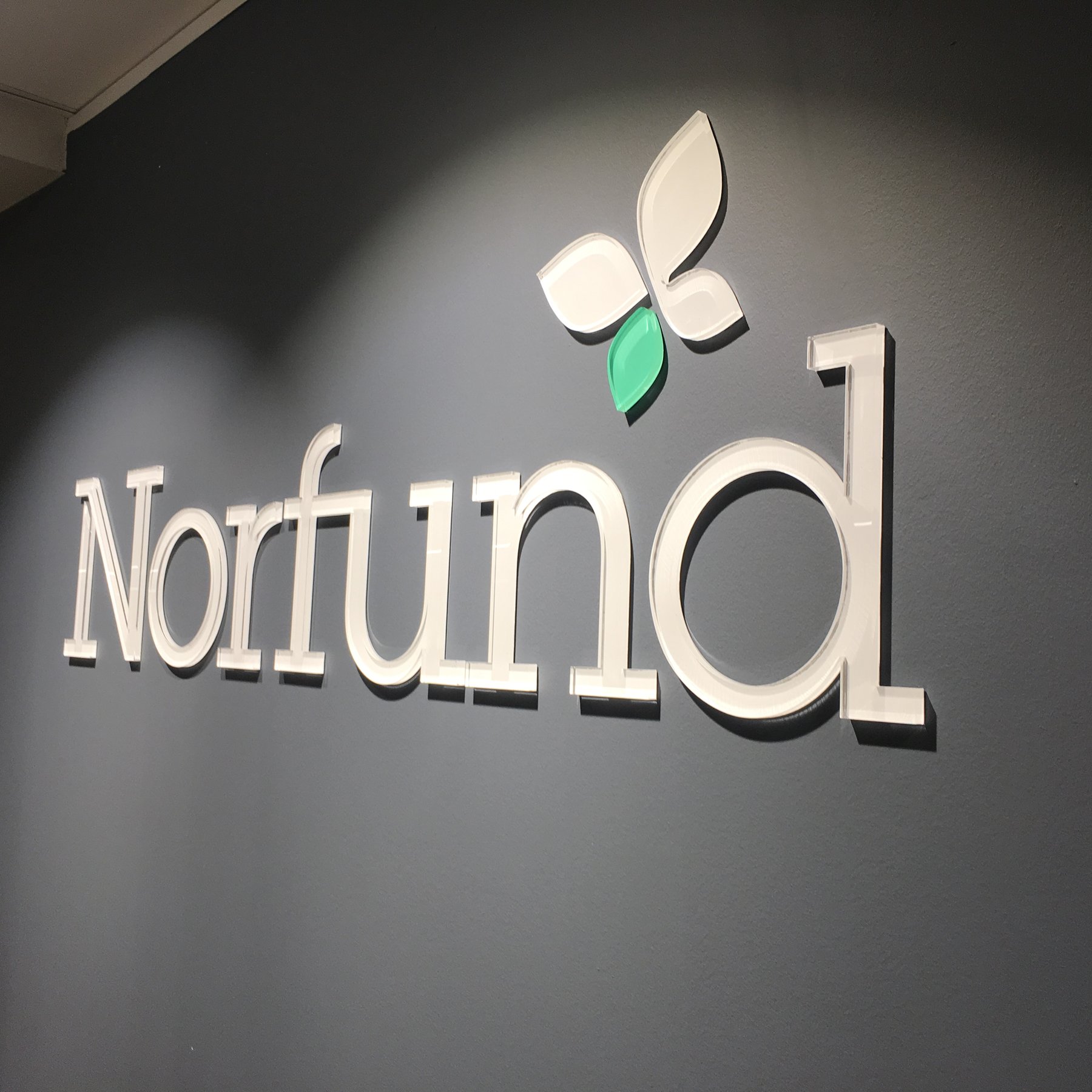 Norfunds logo og bokstaver på mørk vegg